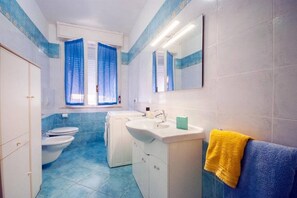 Ein Badezimmer mit Toilette, Waschmaschine, Waschbecken und Spiegel.