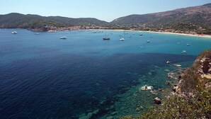 A coastal area with boats, clear water, and a hilly landscape.