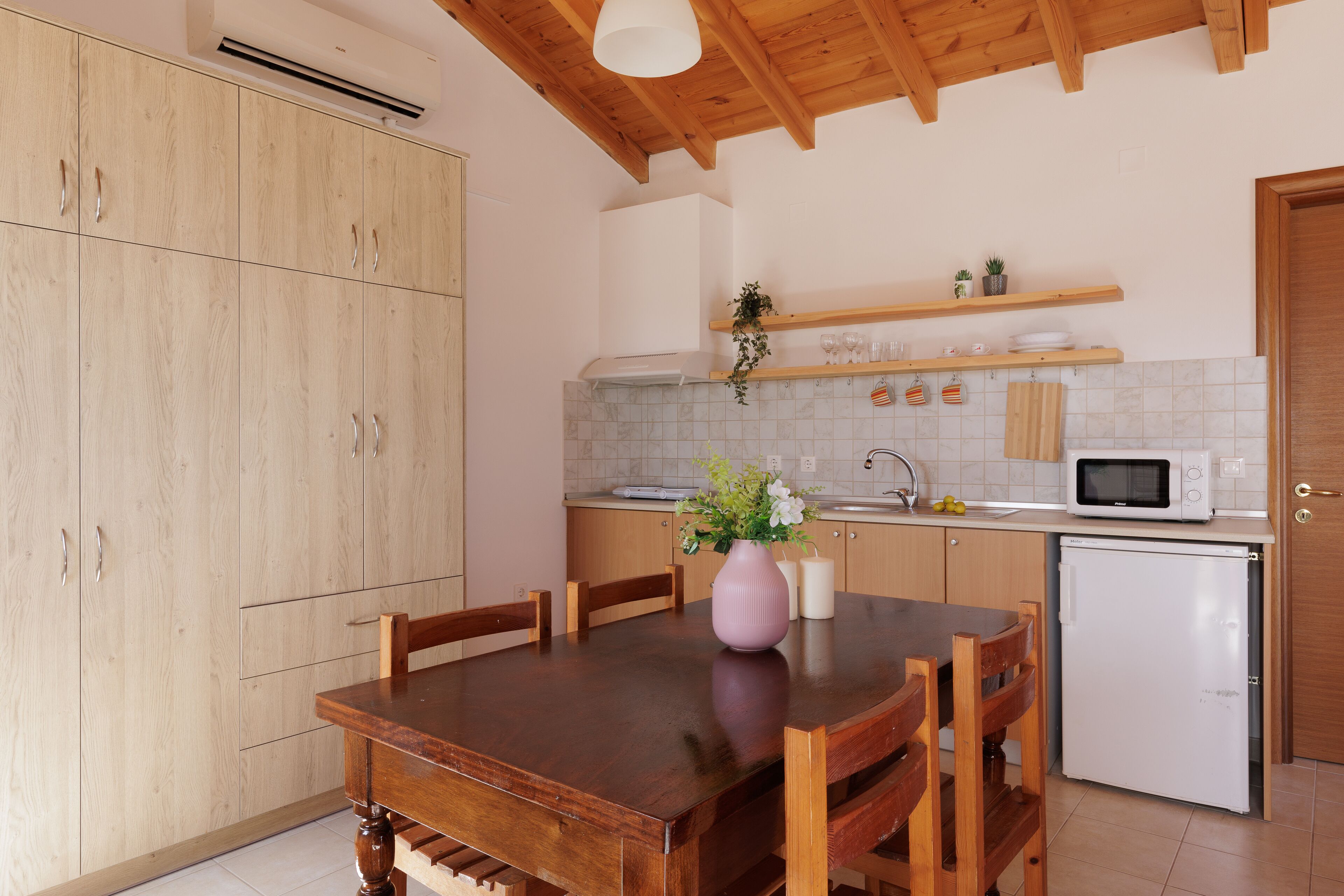 A kitchen with wooden cabinets, a dining table, chairs, a microwave, and a refrigerator.