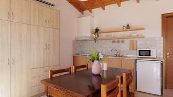 A kitchen with wooden cabinets, a dining table, chairs, a microwave, and a refrigerator.
