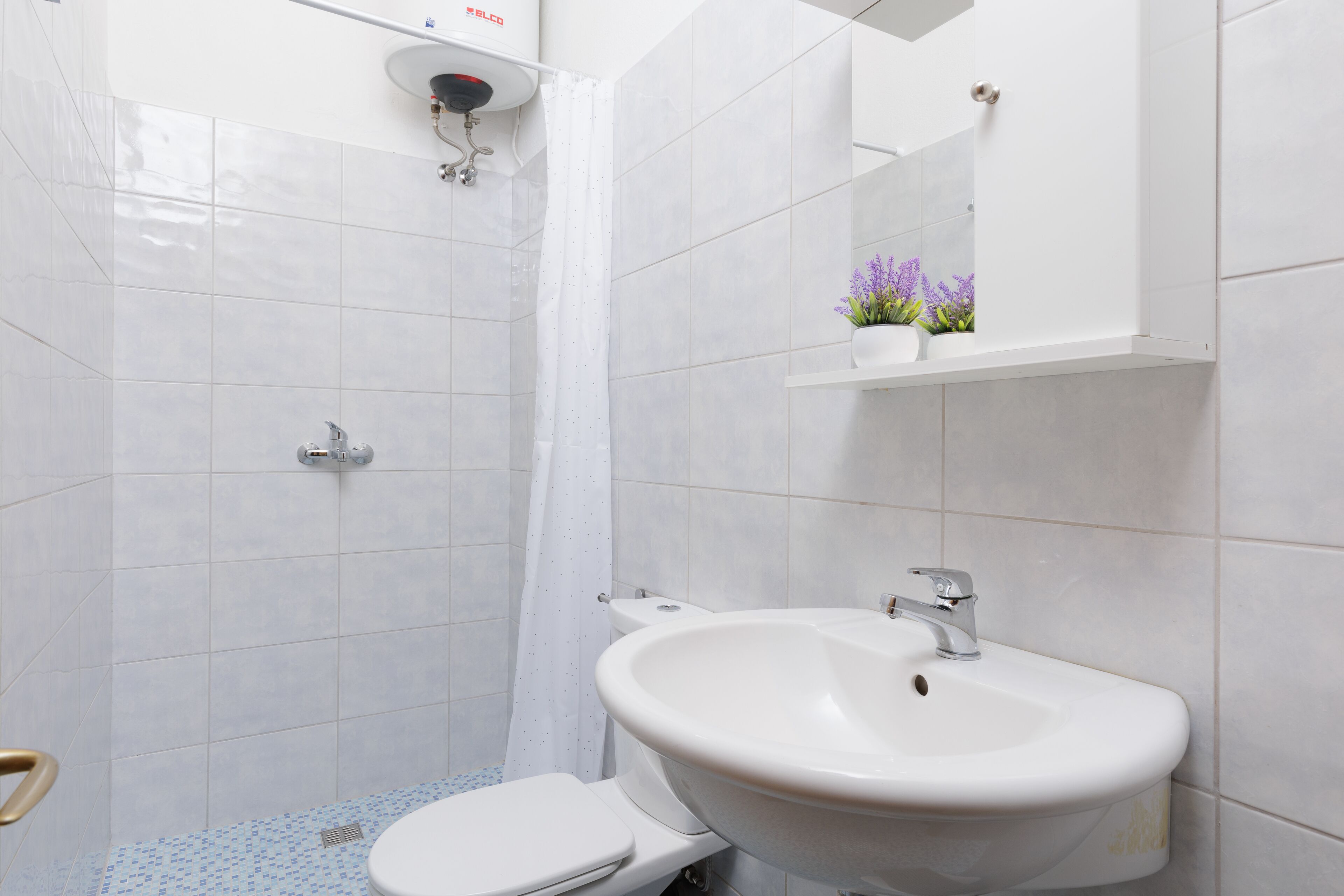 A bathroom with a white sink, toilet, and shower.