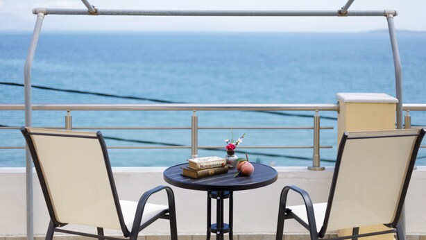 Een balkon met twee stoelen en een kleine tafel, met uitzicht op een wateroppervlak.