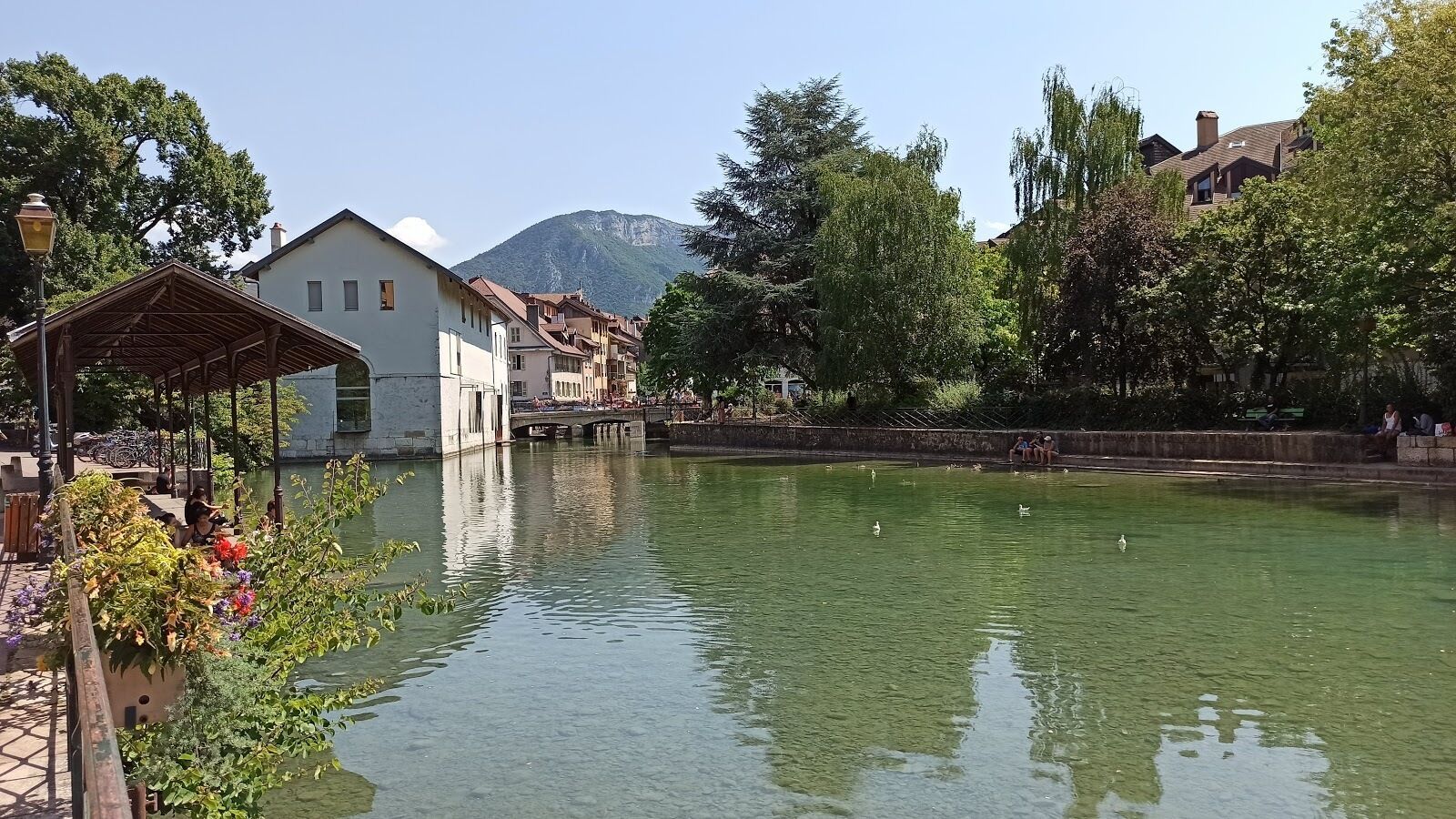 Une vue sur la rivière, avec un pont, des bâtiments et une montagne en arrière-plan.