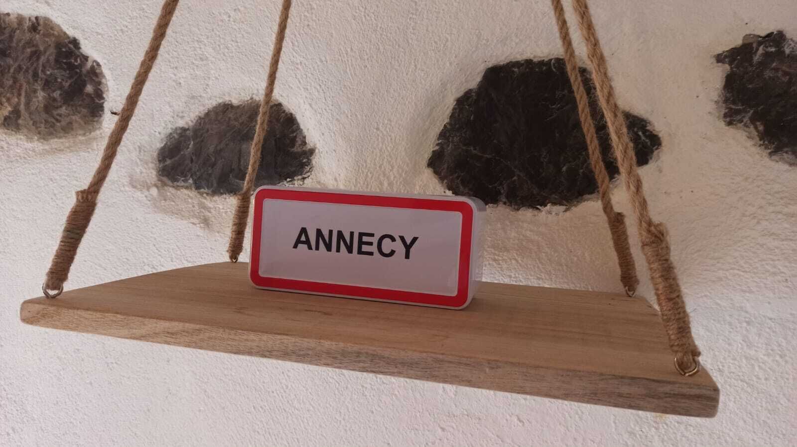 A wooden swing with a sign that reads "ANNECY".