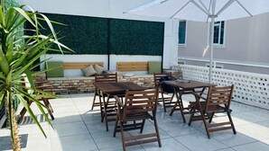 An outdoor patio with a stone bench, wooden tables, and chairs. - The Easy Rooms (Antalya)