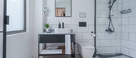 Un baño moderno con lavamanos, inodoro y ducha.