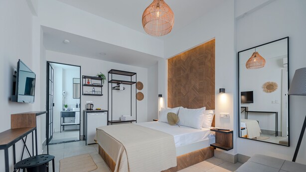 A modern hotel room with a large bed, a TV, a desk, and a bathroom visible through an open door. - The Easy Rooms (Antalya)