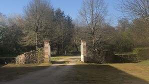 A stone gate with a brick pillar, leading to a rural path surrounded by trees and greenery. - A haven of peace and nature (Sainte-Suzanne-et-Chammes)
