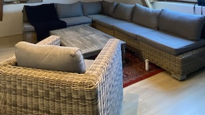 A cozy attic room with a large sectional sofa, a wicker chair, and a skylight. - A haven of peace and nature (Sainte-Suzanne-et-Chammes)