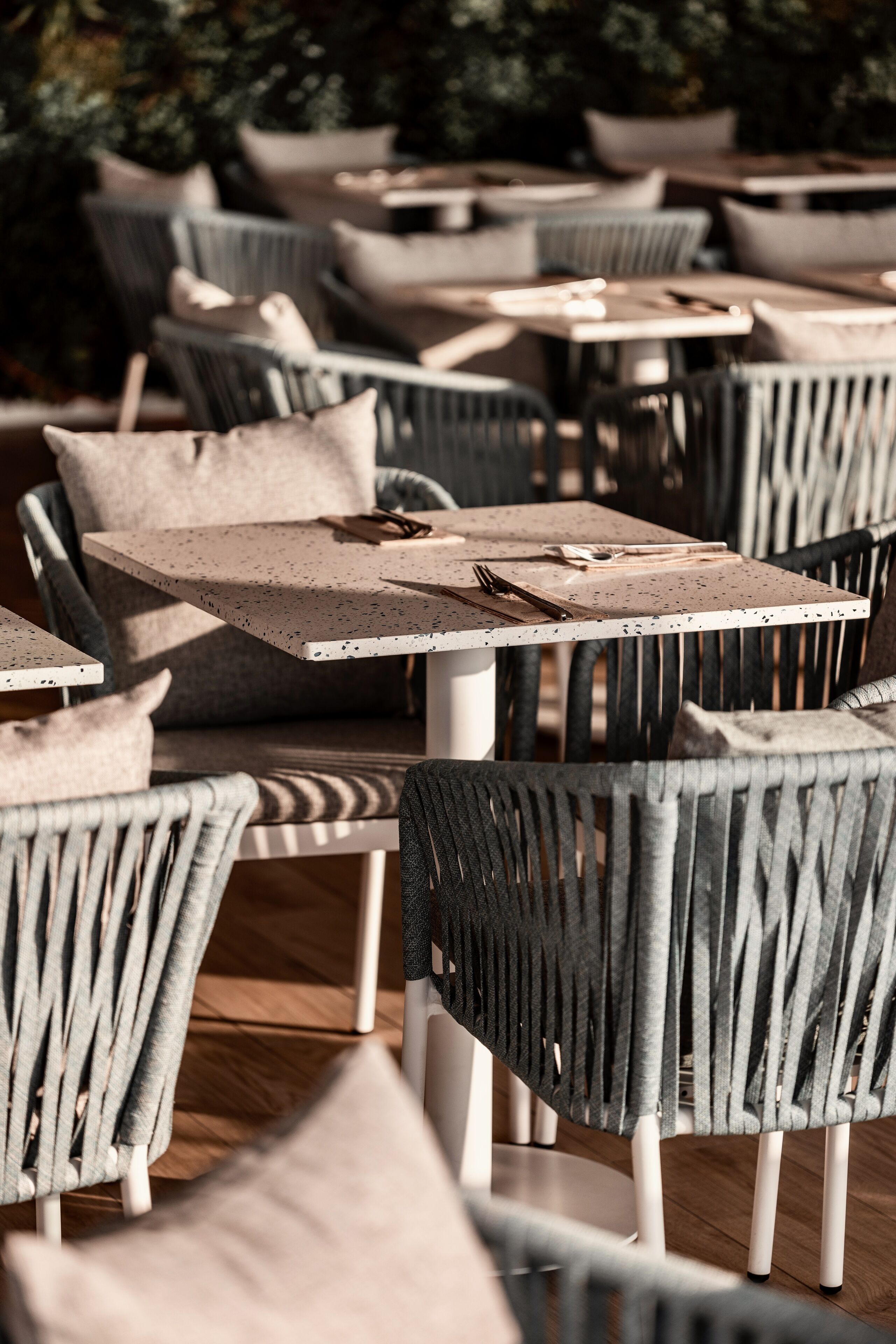 A series of outdoor dining tables and chairs with a modern design, arranged in a casual setting.