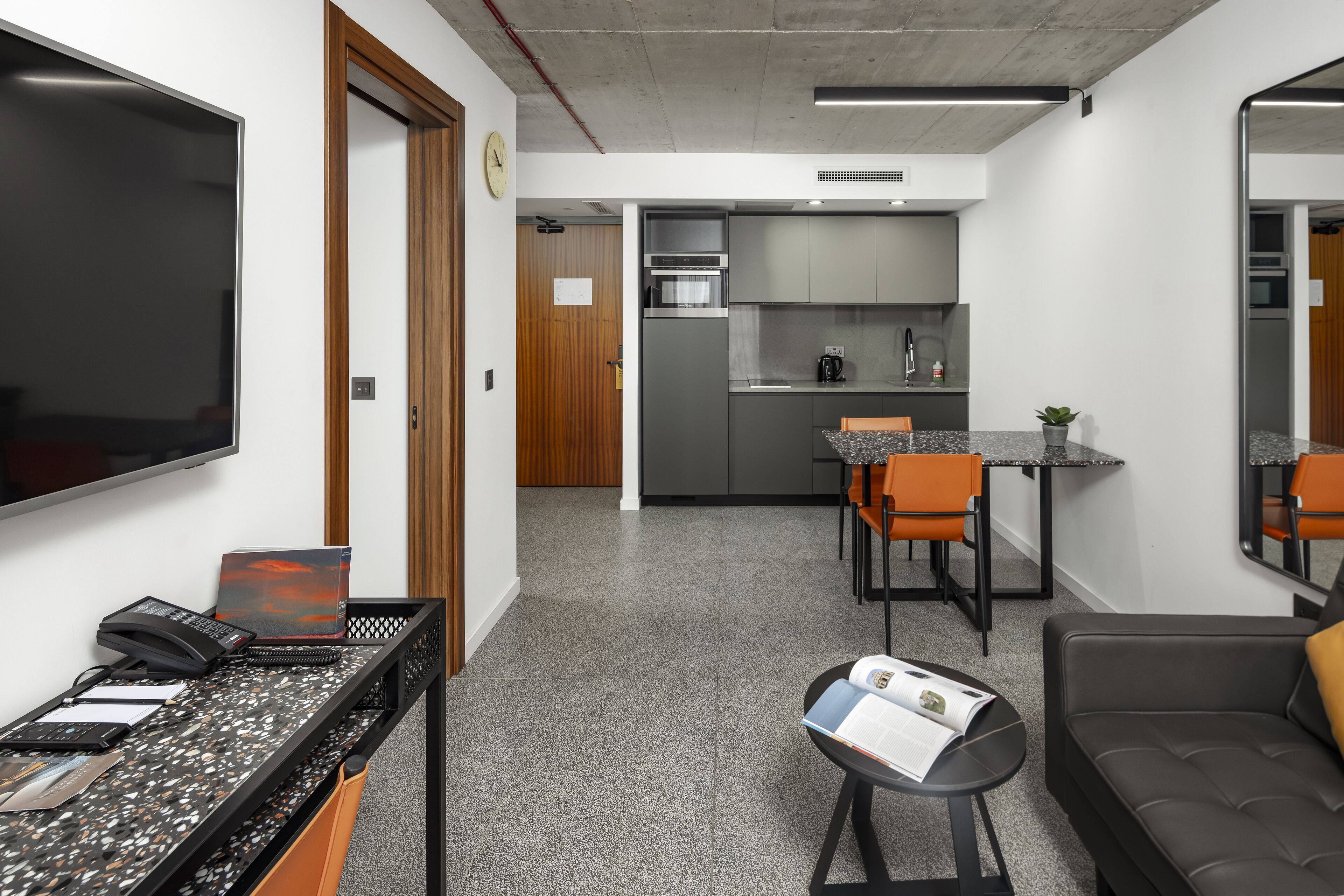 A modern kitchen with grey cabinets, a stainless steel oven, and a coffee machine.
