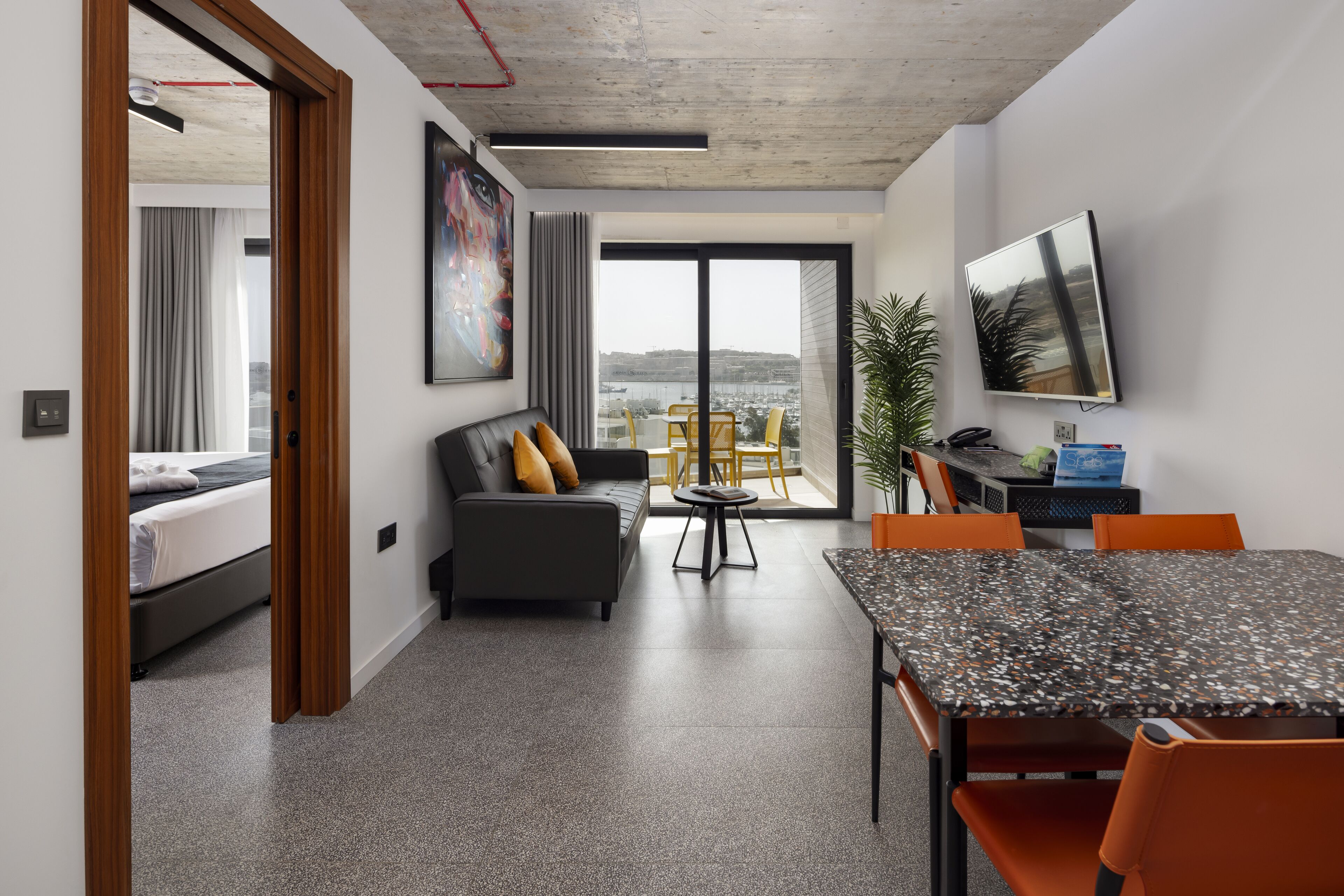 A modern living room with a sofa, a dining table, and a TV.