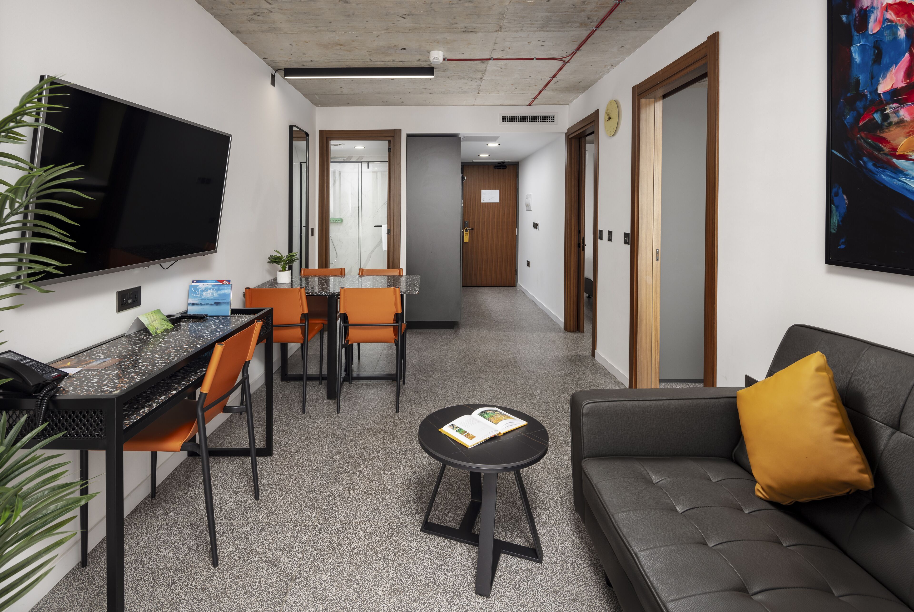 Un salon moderne comprenant un canapé, une table basse, un téléviseur et un coin repas avec des chaises et une table.