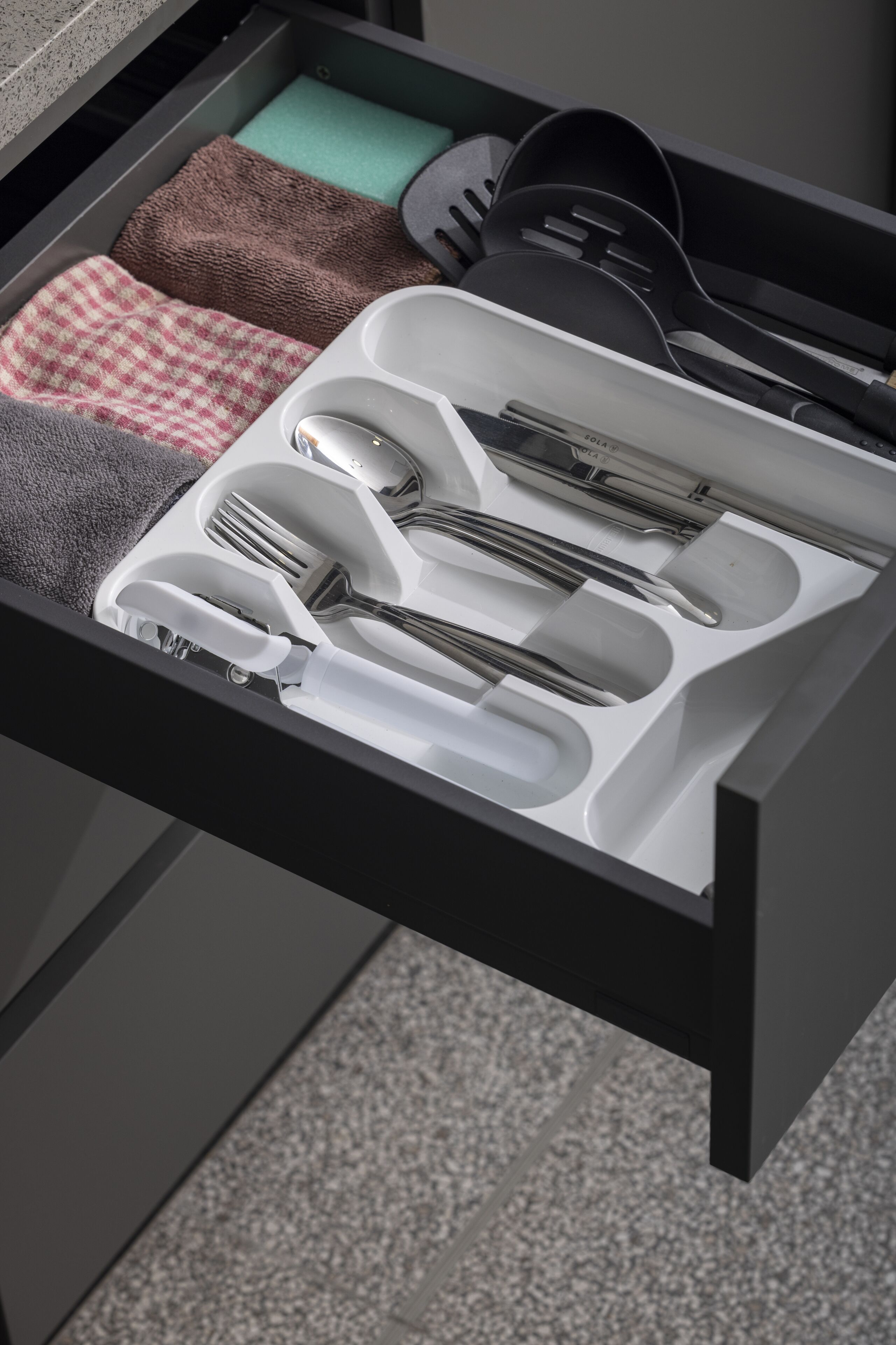 A drawer with neatly organized kitchen utensils including a knife set, spatulas, and a spoon set.