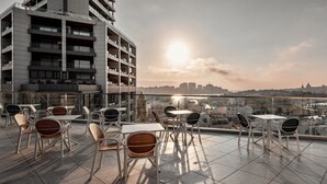 Terraza en la azotea con mobiliario exterior y vistas a un paisaje urbano.