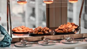 A buffet with various pastries and a spoonful of food on a plate.