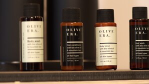 Fire flasker med produkter fra Olive Era står på en hylde.