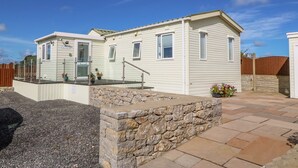 Une maison mobile avec un mur en pierre et une terrasse dallée.