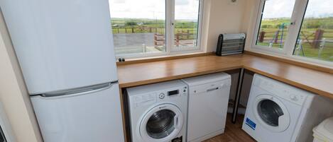 A compact kitchen with a refrigerator, two washing machines, and a toaster.
