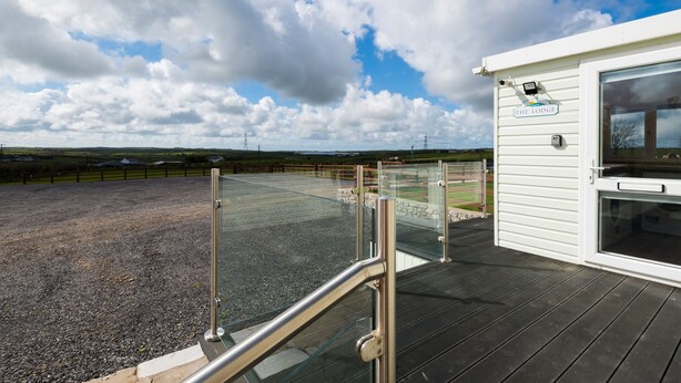 Vue depuis une terrasse du Lodge, avec un espace recouvert de gravier, une rambarde en verre et un bâtiment blanc portant une enseigne.