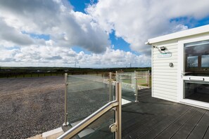 Vue depuis une terrasse du Lodge, avec un espace recouvert de gravier, une rambarde en verre et un bâtiment blanc portant une enseigne.
