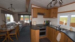 Une cuisine de taille réduite, avec des meubles de rangement en bois, une cuisinière et un évier.