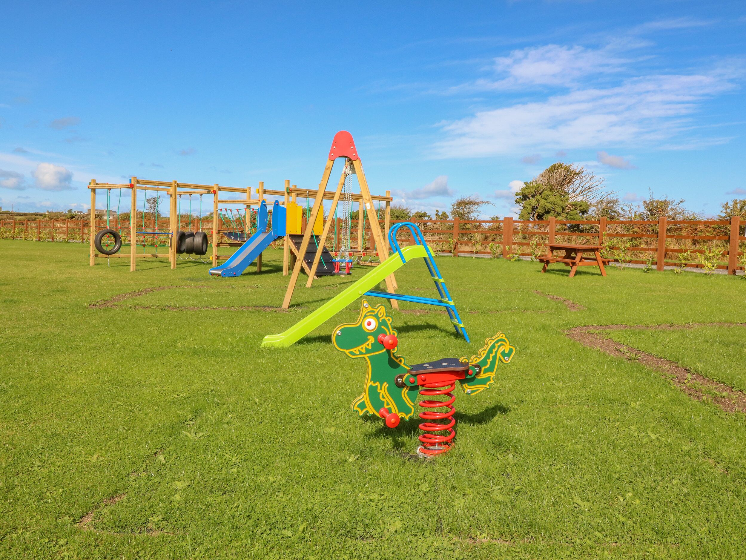 Un parque infantil con columpios, tobogán y estructura para escalar.