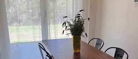 Un coin repas avec une table en bois, des chaises noires et une plante en pot.