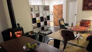 Un salon chaleureux avec une table à manger en bois, une bibliothèque, une cheminée et un coin repas avec des chaises et une table mise pour le repas.