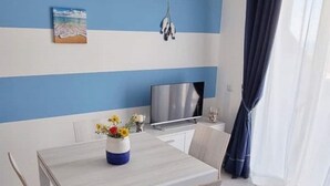 Une chambre moderne équipée d’un téléviseur à écran plat, d’un tableau et d’un vase rempli de fleurs posé sur une table.
