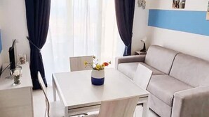 Un salon moderne avec un canapé, une table à manger agrémentée d’un vase de fleurs et un mur d’accent bleu.