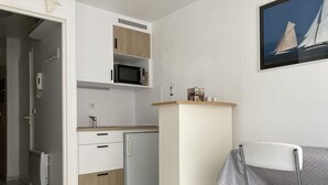 Una cocina compacta con microondas, un refrigerador pequeño y un mueble de madera sobre el lavamanos.