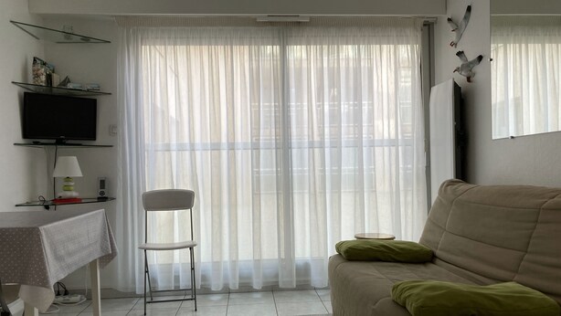 Una sala de estar con un sofá, una silla, un televisor y una mesa con una lámpara.