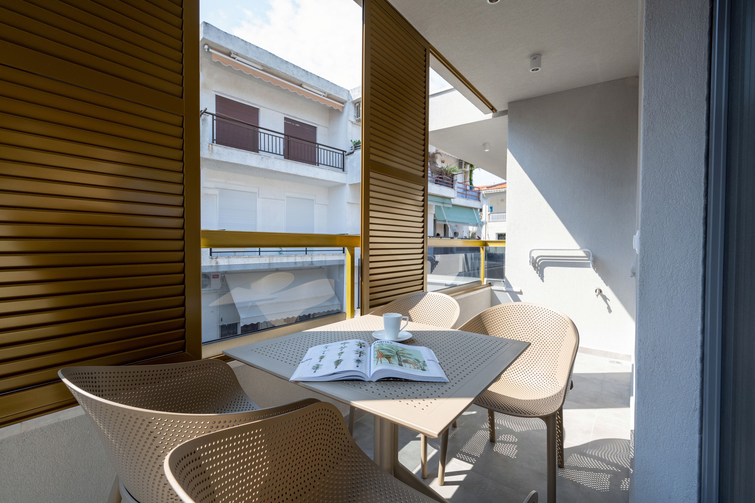 A balcony with a table, chairs, and a book.