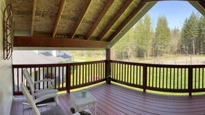 Eine überdachte Terrasse mit Holzgeländer, Blick auf einen Wald und einen klaren Himmel.