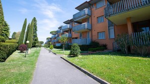 A row of modern apartment buildings with balconies, a paved walkway, and well-maintained greenery. - Appartamento Luisa e Francesco (Peschiera del Garda)