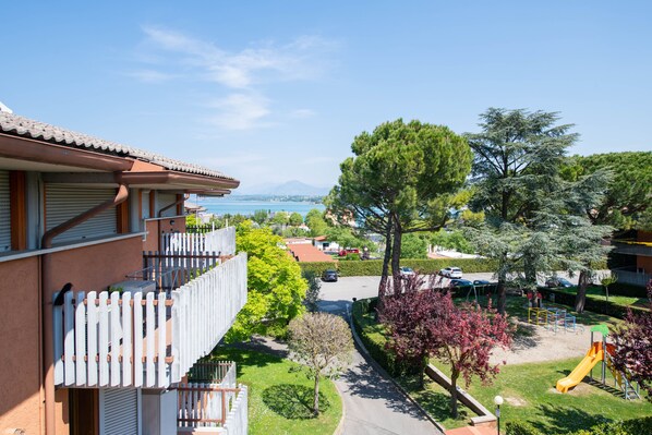 A residential area with a view of a body of water, a playground, and a building with a balcony.