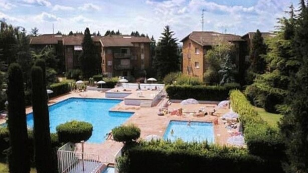 A hotel courtyard with multiple swimming pools, surrounded by well-maintained hedges and trees. - Appartamento Luisa e Francesco (Peschiera del Garda)