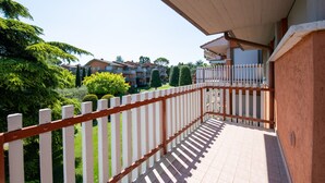 A balcony with a white picket fence, a tiled floor, and a view of residential buildings and greenery. - Appartamento Luisa e Francesco (Peschiera del Garda)