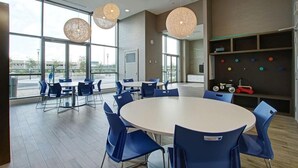 Una sala de conferencias moderna con mesas redondas, sillas azules y ventanas amplias.