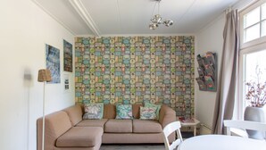 A cozy living room with a beige sectional sofa, a white dining table, and a patterned wallpaper. - B&B Koepel Enschede (Enschede)