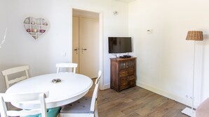A room with a round white table, white chairs, a wooden cabinet with a TV, and a heart-shaped shelf. - B&B Koepel Enschede (Enschede)