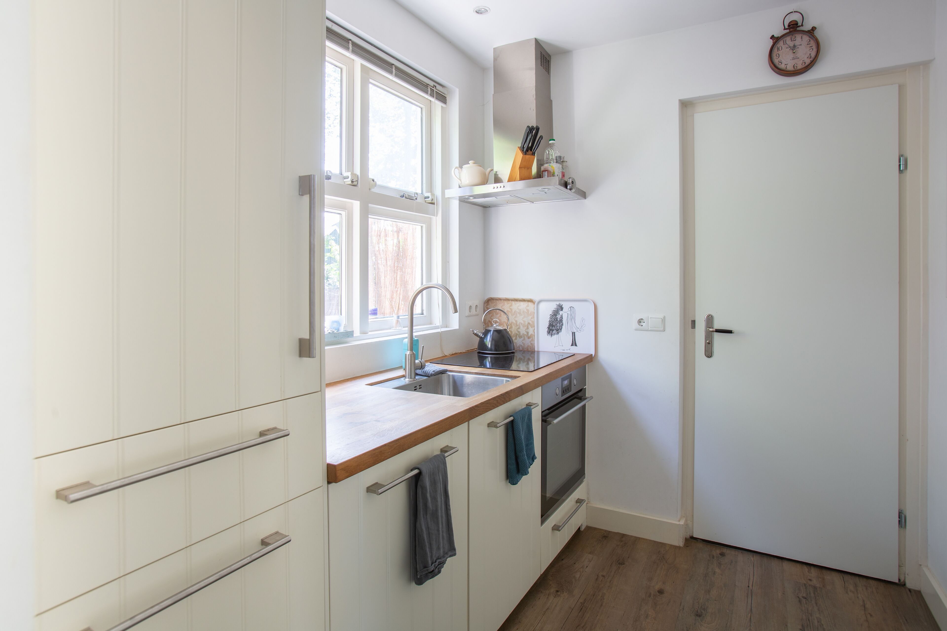 Cocina pequeña con ventana, pileta, estufa y una puerta.
