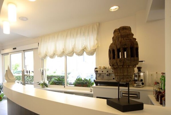 Una cocina moderna con encimera blanca, una cafetera y una escultura decorativa.