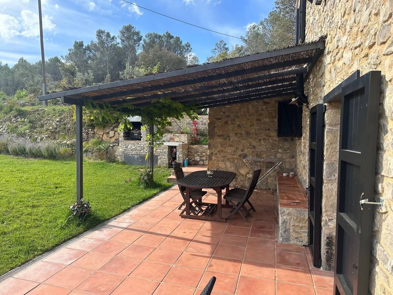 Une terrasse avec une table et des chaises, un mur en pierre et une porte.