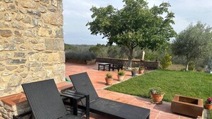 Un patio con dos sillones negros, una mesita y plantas en macetas.