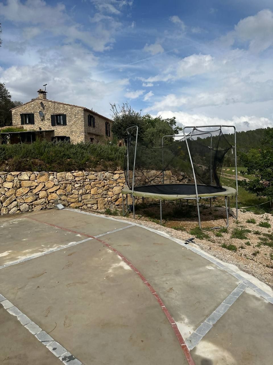 A stone wall, a trampoline, and a stone house with a chimney.