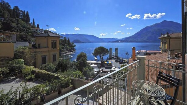 Un balcon avec vue sur un lac, des bâtiments et des montagnes.