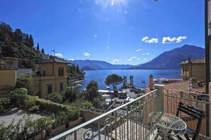 A balcony with a view of a lake, buildings, and mountains. - Casa Sole with lake view (Varenna)