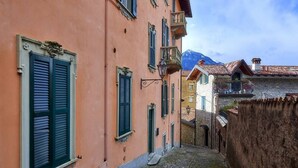 Une ruelle étroite pavée, bordée d’immeubles à l’architecture traditionnelle, avec des balcons et des volets.